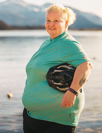 Radtrikot große Größen Damen – Kerstin im türkisfarbenen Fahrradtrikot mit Helm am See