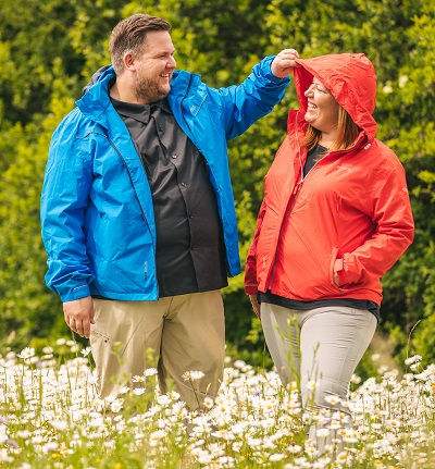 Glückliches Paar in blauer und roter Outdoorjacke in Übergröße auf einer Blumenwiese